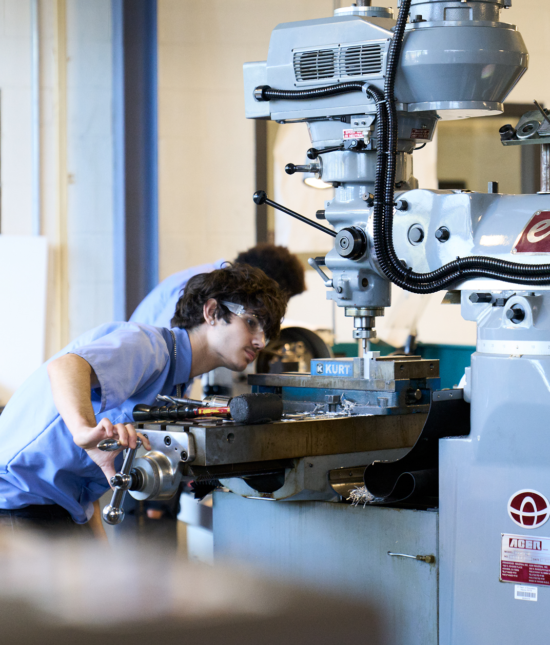 A young man working attentively at a machine in a manufacturing plant